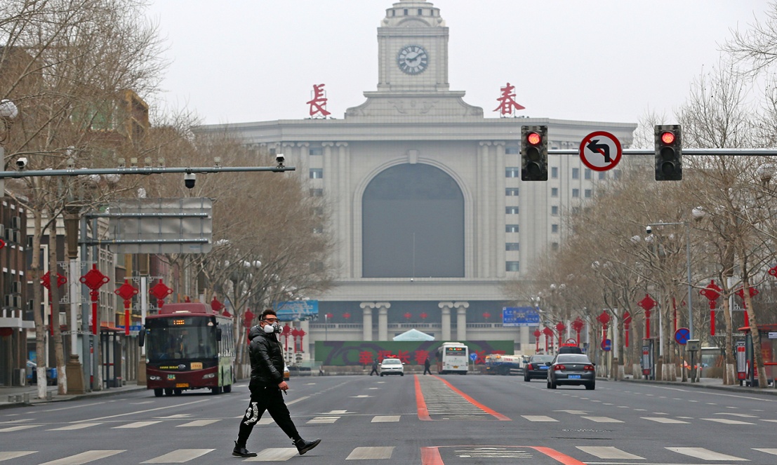 2月12日,长春火车站附近,一位市民戴着防毒面具走过街头 摄影 白石