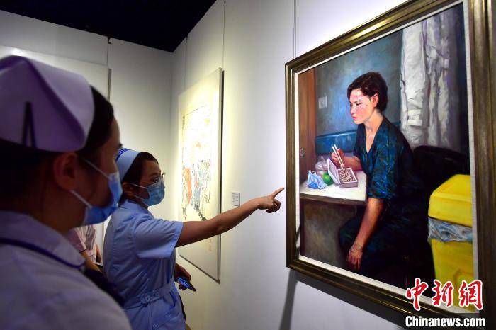 图为福建援鄂医护人员在观看展出的油画作品《战疫天使的晚餐》。　张斌 摄