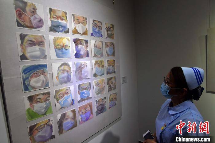 图为福建援鄂医护人员在观看展出的水彩画作品《自觉防疫》。　张斌 摄