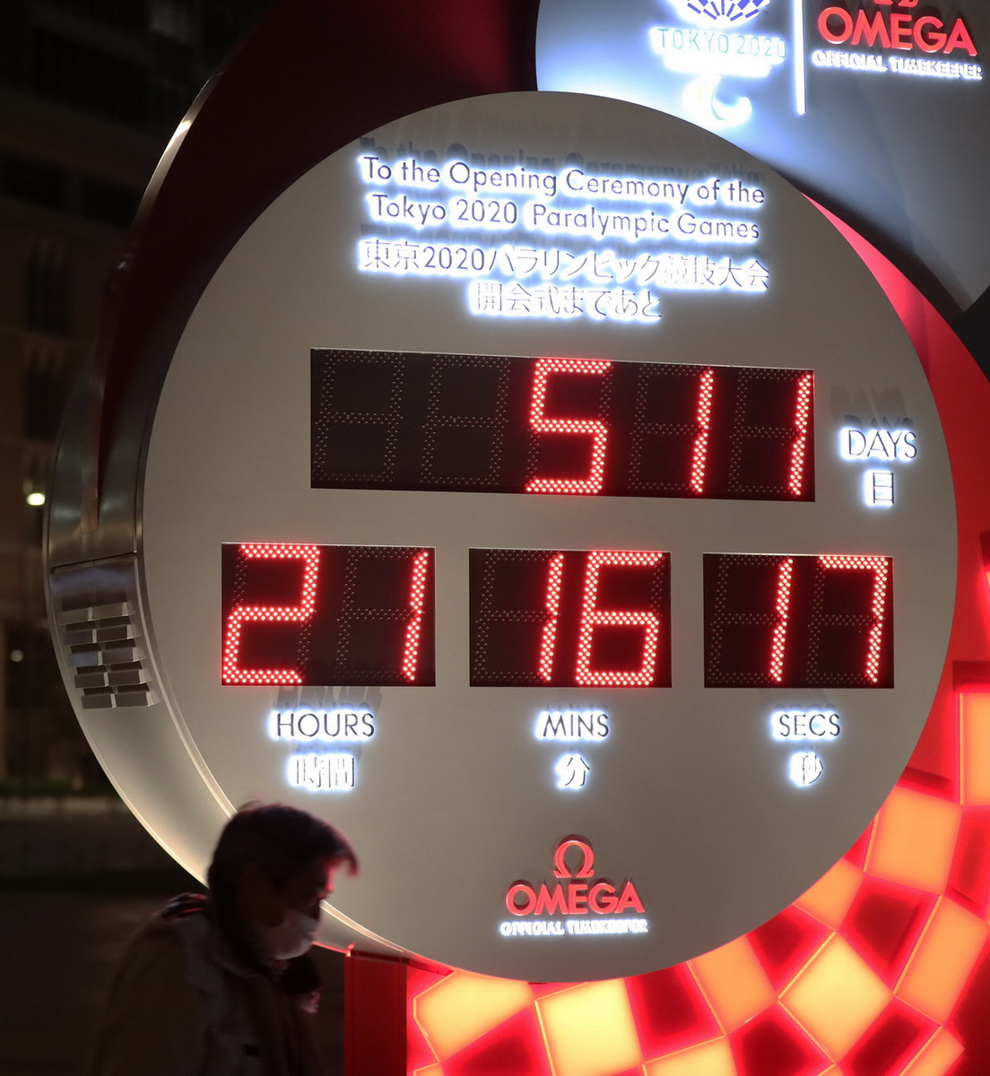 3月30日，行人经过日本东京站前显示东京残奥会开幕式倒计时的电子钟，电子钟已根据新宣布的开幕时间进行调整。