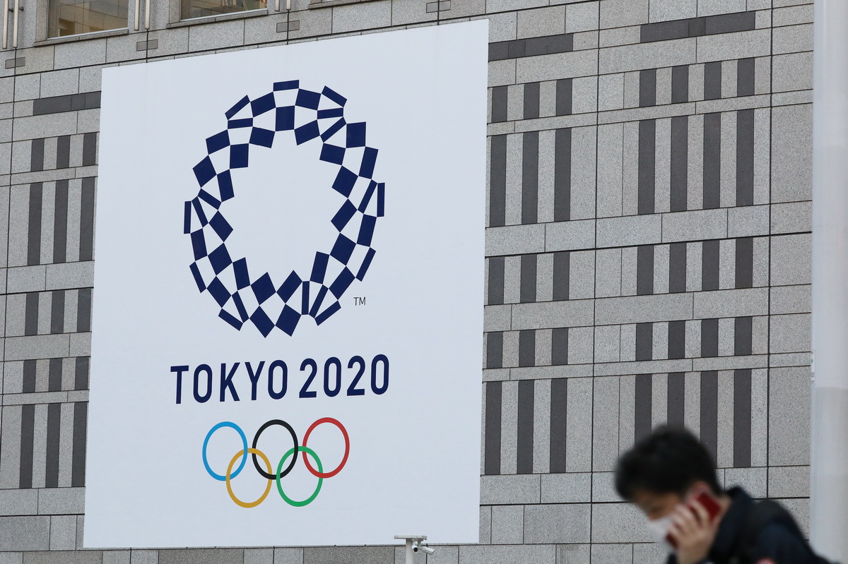 行人经过日本东京都厅前的东京奥运会会徽 （2020年3月25日摄）。
