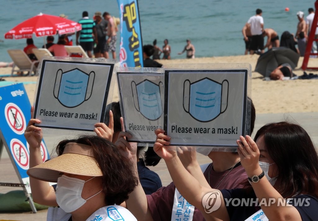 7月5日，在釜山市海云台海水浴场，市民呼吁访客佩戴口罩。图源：韩联社