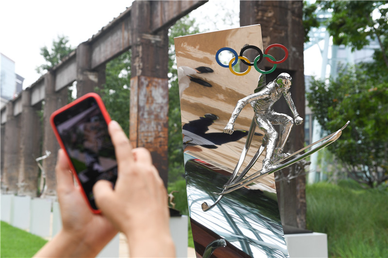 7月13日，参观者在拍摄展出的雕塑作品《自由式滑雪——翱》。