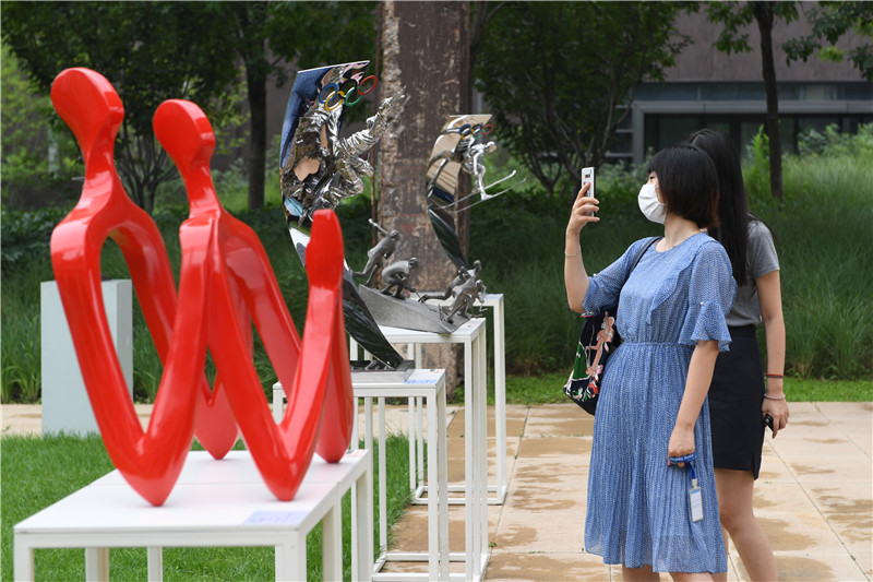 7月13日，参观者在参观展出的雕塑作品。