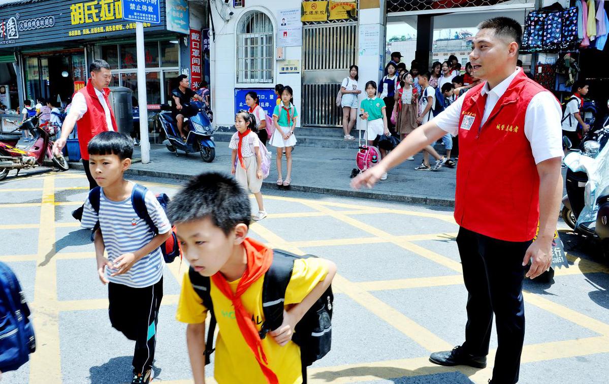 局黨員幹部正在該市農貿市場學校門口,義務為放學回家的孩子保駕護航